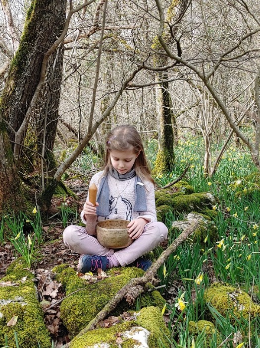 Une petite fille joue un bol chantant dans la forêt