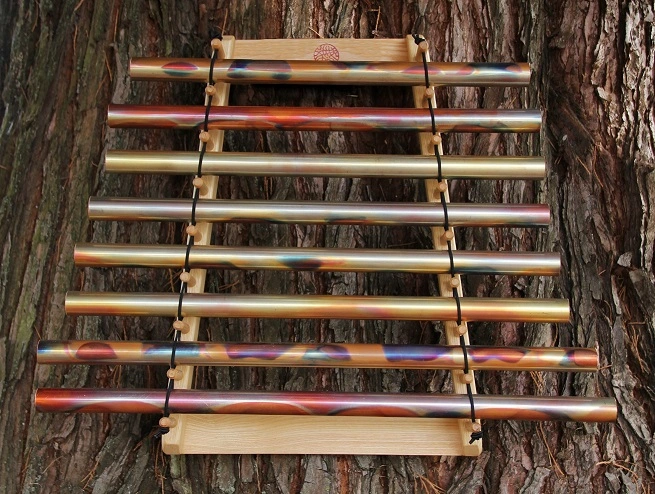 Harpe chakra en laiton, contre un tronc d'arbre.